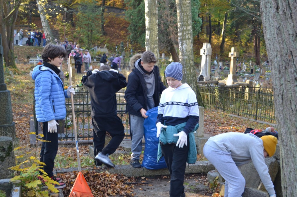 grupa uczniów porządkuje groby