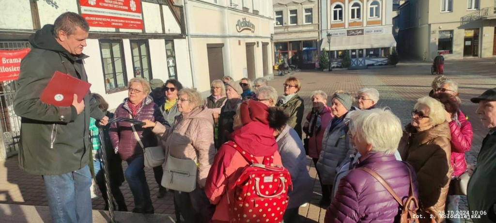 pracownik Muzeum Piaśnickiego rozmawia z grupą seniorów na placu w Wejherowie