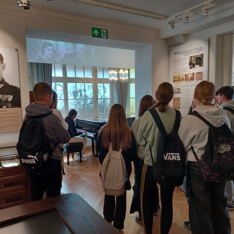 młodzież słucha jak ich koleżanka gra na fortepianie w Muzeum Piaśnickim