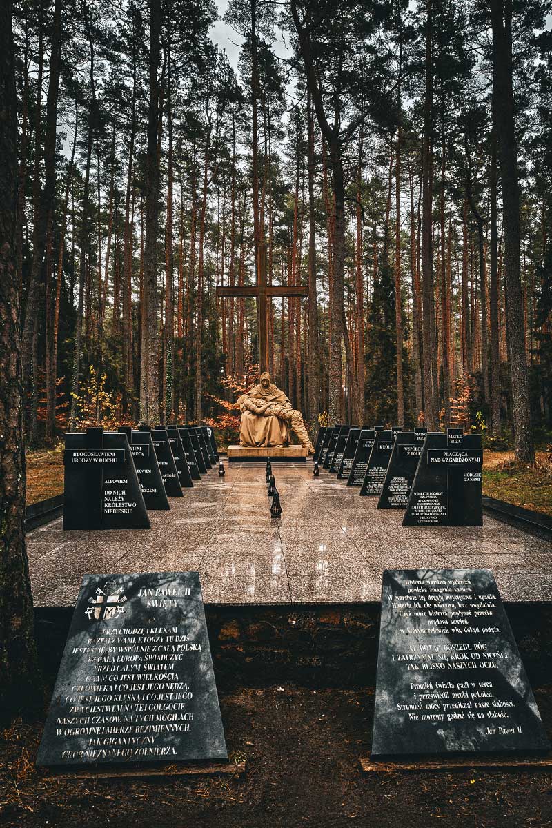 a sculpture of Mary holding Jesus and prayer boards