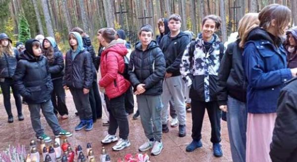 uczniowie zapalają znicze pod pomnikiem w Lesie Piaśnickim