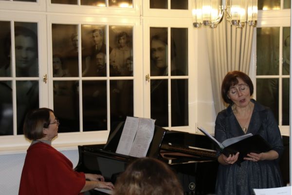 dwie kobiety jedna gra na fortepianie, druga śpiewa kolędę