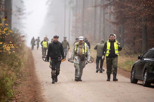 pracownicy IPN idą ze sprzętem do wykrywaczy metali w Lesie Piaśnickim