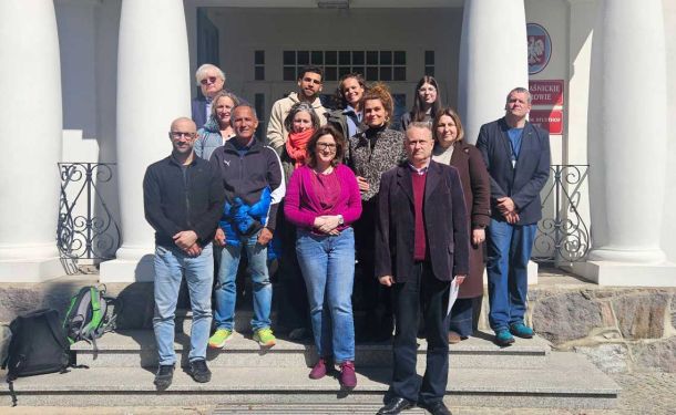 pracownicy muzeum z gośćmi pozują do zdjęcia przed muzeum