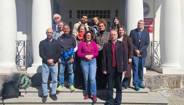 pracownicy muzeum z gośćmi pozują do zdjęcia przed muzeum