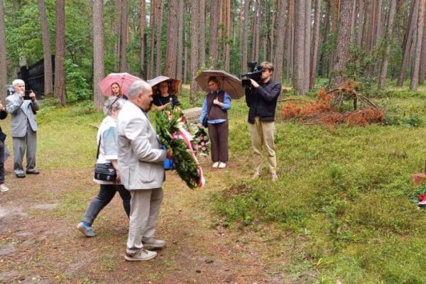 grupa ludzi składa wieńce pod pomnikiem