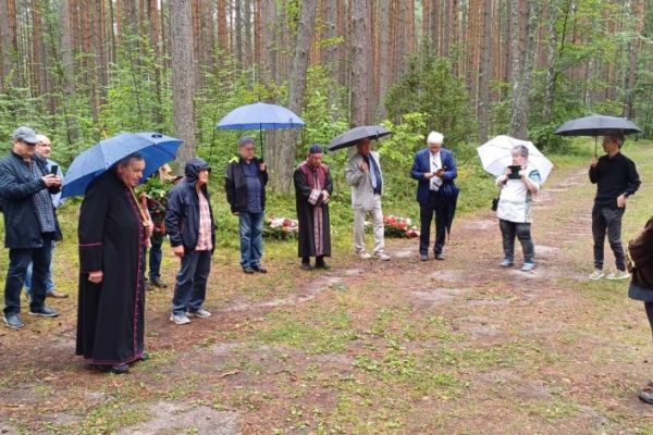 grupa ludzi modli się w Lasach Piaśnickich przy pomniku