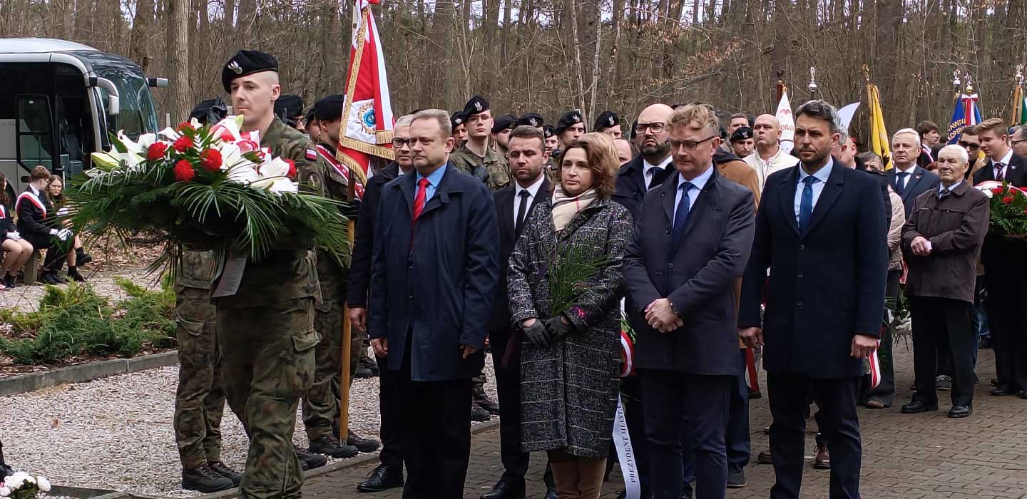 pracownicy Muzeum przed pomnikiem ofiar zbrodni piaśnickiej