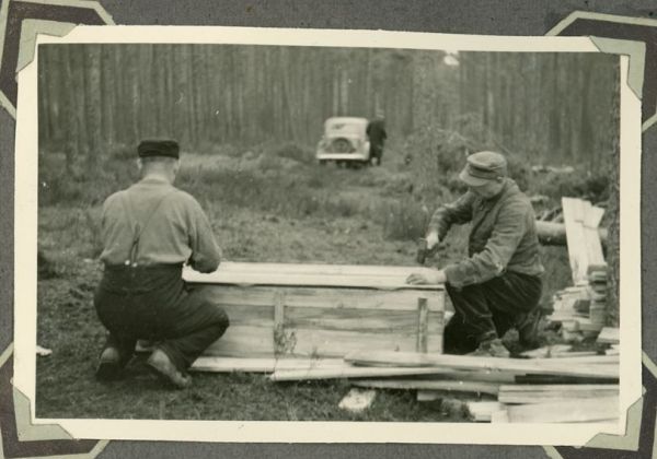 mężczyźni wbijają gwoździe w trumnę w lasach piaśnickich
